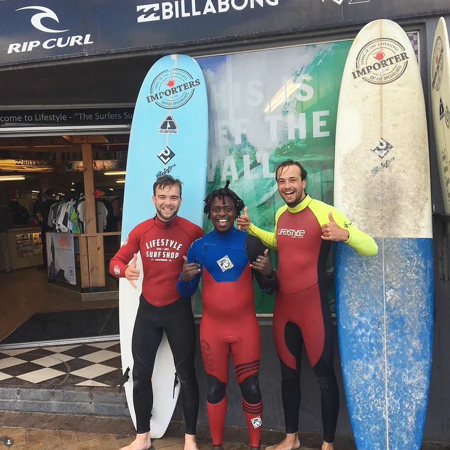 Kwezi with two students outside the surf shop